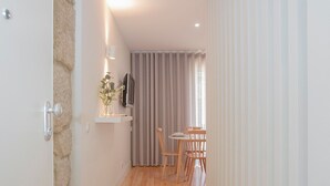 A narrow hallway with wooden flooring, a dining area with a table and chairs, and a television mounted on the wall. - Liiiving in Porto Charming Downtown Delight I (Porto)
