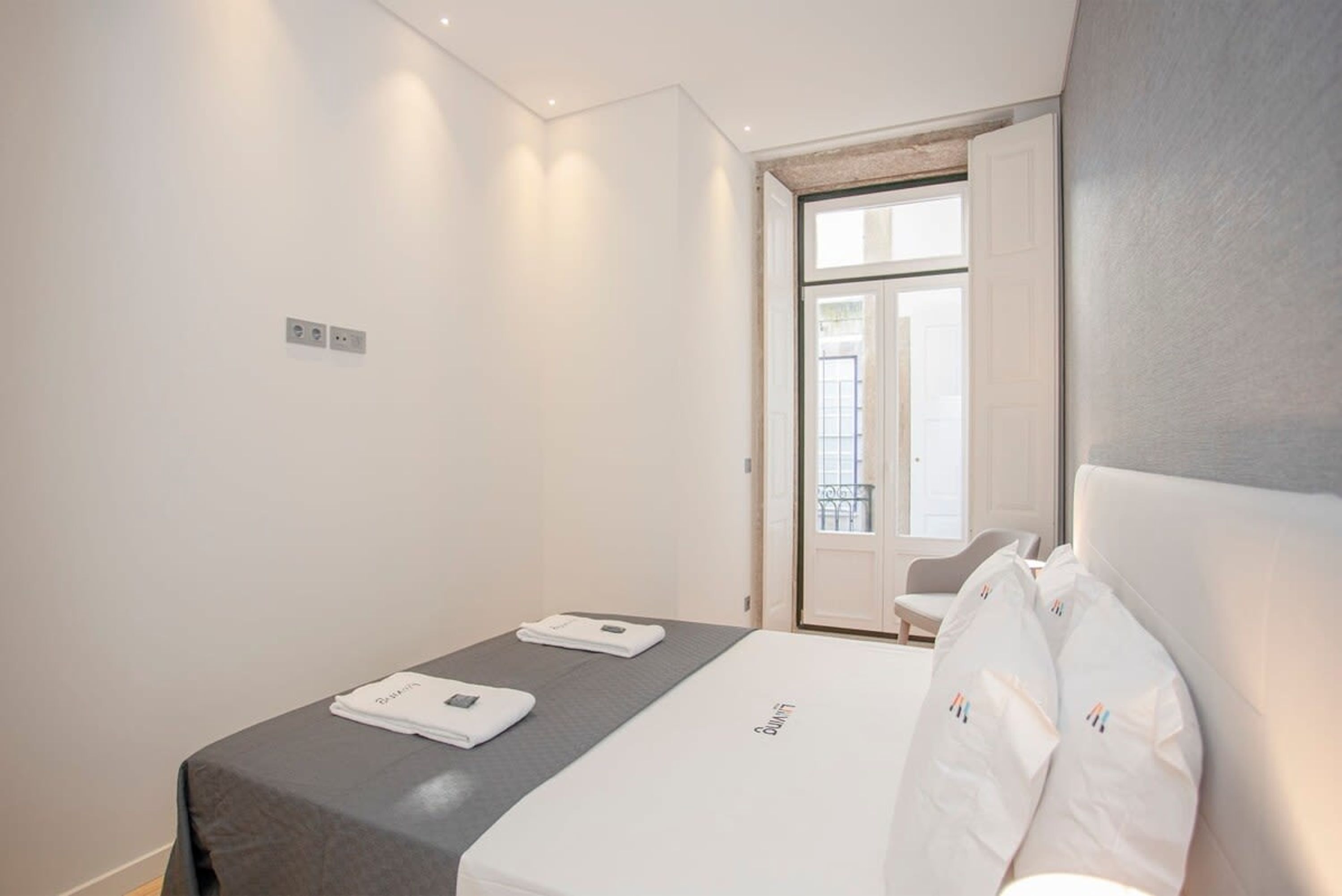 Una habitación de hotel moderna con una cama, una mesita y una silla.