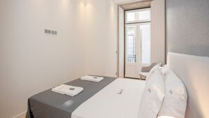 Una habitación de hotel moderna con una cama, una mesita y una silla.