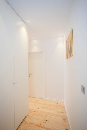 A narrow hallway with wooden flooring, white walls, and a door at the end. - Liiiving in Porto-mouzinho Residence Apartment 2T (Porto)