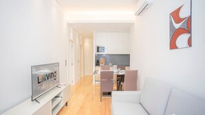 Una sala de estar moderna con un televisor de pantalla plana, un sofá y un comedor con sillas y una mesa.