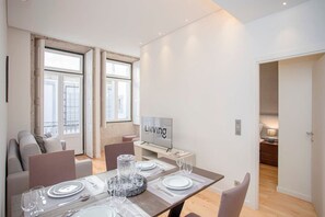 A modern living room with a dining area, a television, and a view of the outside. - Liiiving in Porto-mouzinho Residence Apartment 2T (Porto)