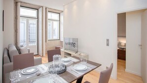 Una sala moderna con comedor, televisor y vistas al exterior.