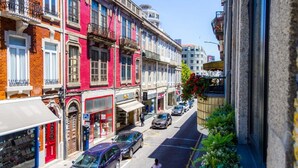 Une rue étroite bordée de bâtiments aux couleurs vives, dont certains sont dotés de balcons et de devantures de magasins.