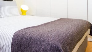 Une chambre à coucher avec un lit, une lampe de chevet et une armoire.