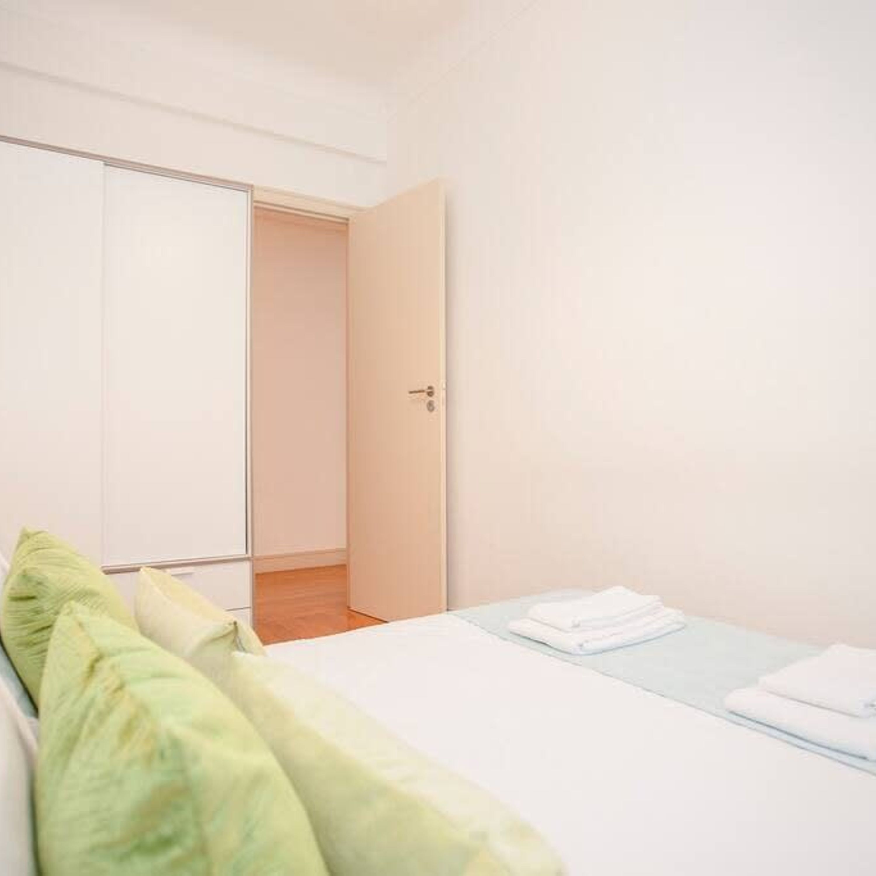 A bedroom with a bed, a wardrobe, and a door leading to another room.