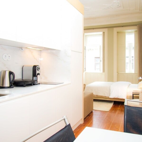 Une chambre d’hôtel de taille réduite, dotée d’une kitchenette, d’un lit et d’une fenêtre.