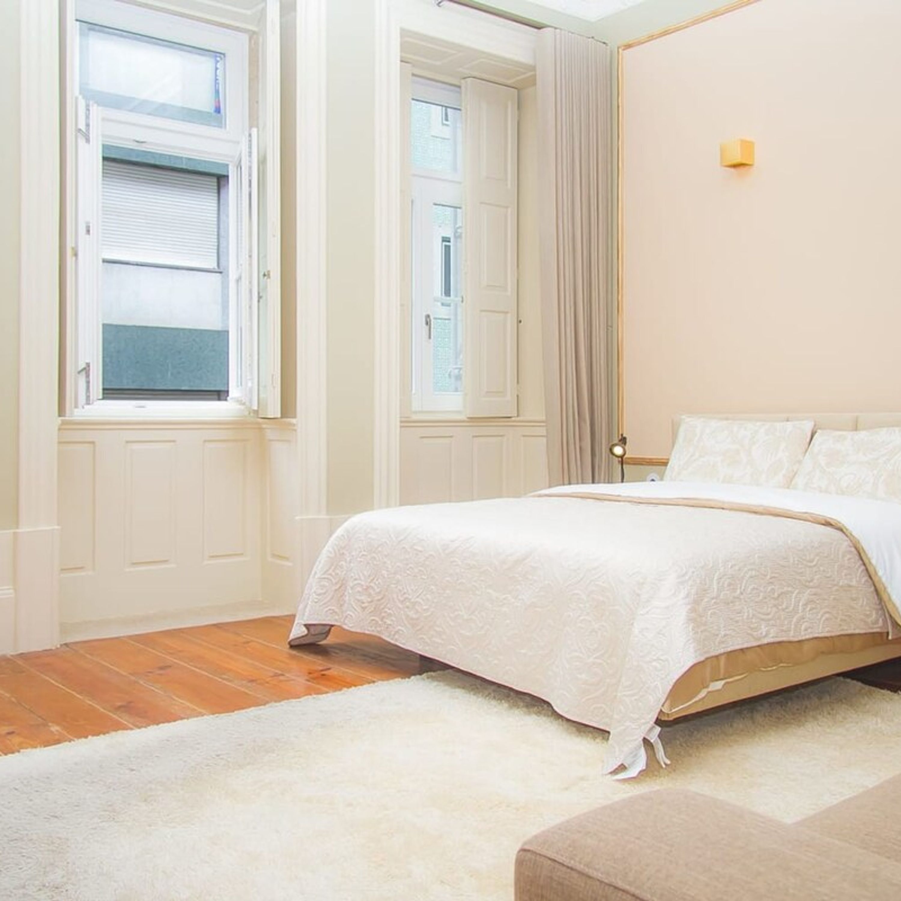 Une chambre à coucher avec un lit, une table de chevet, une lampe et une fenêtre avec des rideaux.