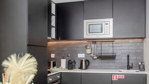 Cozinha moderna com armários escuros, um micro-ondas e uma pia.