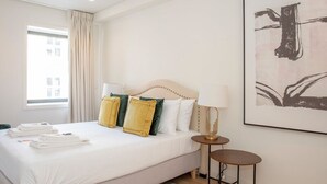 Une chambre d’hôtel avec un grand lit, une table de chevet avec une lampe et une œuvre d’art encadrée au mur.