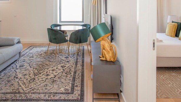 Un salon moderne comprenant un canapé, une table ronde avec des chaises, une lampe décorative et un petit meuble.
