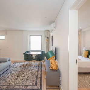 Una sala de estar moderna con un sofá, una mesa redonda con sillas, una lámpara decorativa y un mueble bajo.