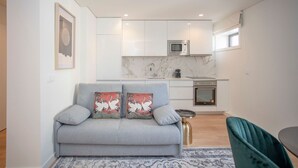 Un salon moderne avec un canapé gris, un tapis à motifs et un coin repas comprenant une table et des chaises.