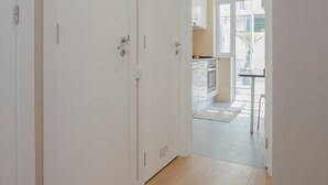 A corridor leading to a kitchen with white cabinets and a tiled floor. - Liiiving in Porto Terrace Downtown Apartment (Porto)