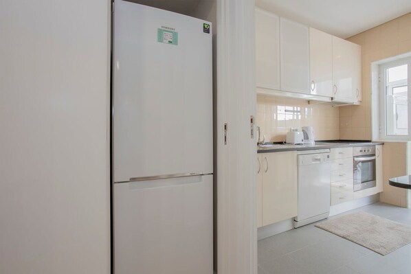 A modern kitchen with white cabinets, a built-in oven, and a stainless steel refrigerator. - Liiiving in Porto Terrace Downtown Apartment (Porto)