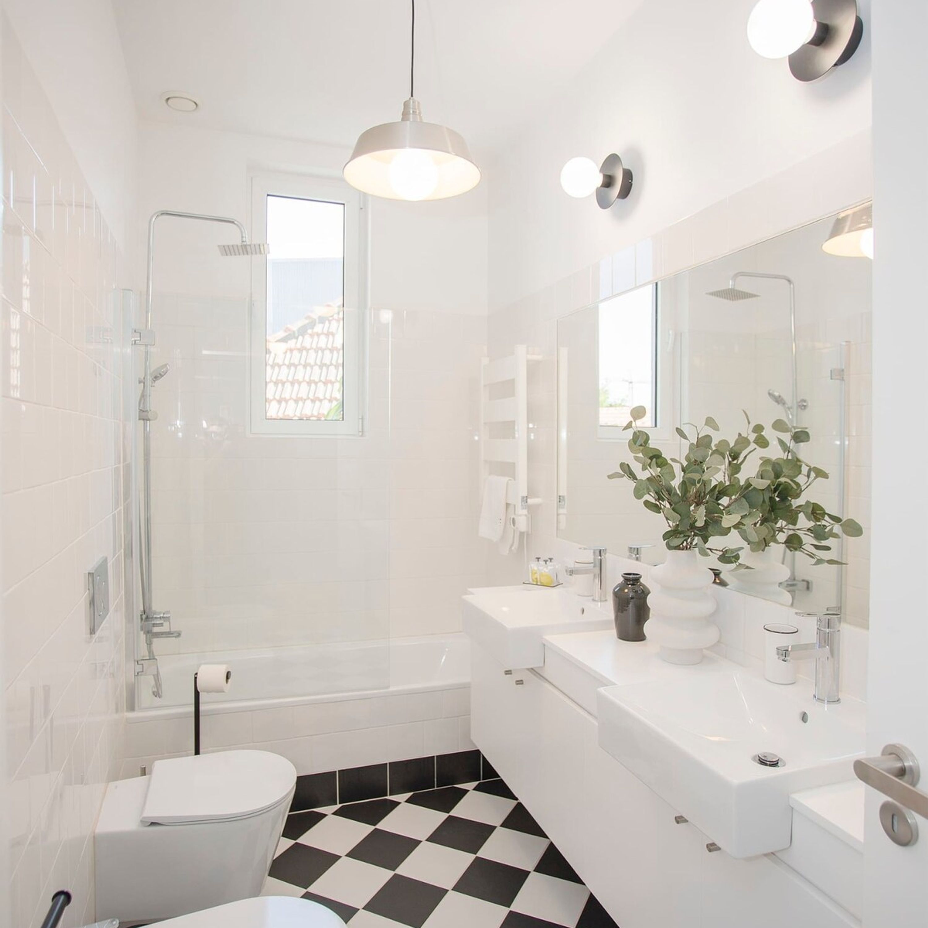 A modern bathroom with a shower, toilet, sink, and a large mirror.