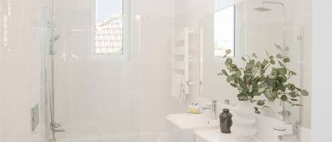 A modern bathroom with a shower, toilet, sink, and a large mirror.