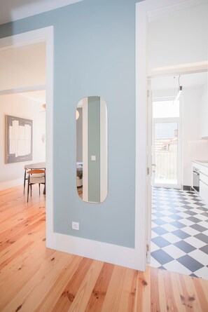A room with a wooden floor, a white door, and a view of a balcony with a checkered floor. - Liiiving in Porto - Art Design Apartment II (Porto)