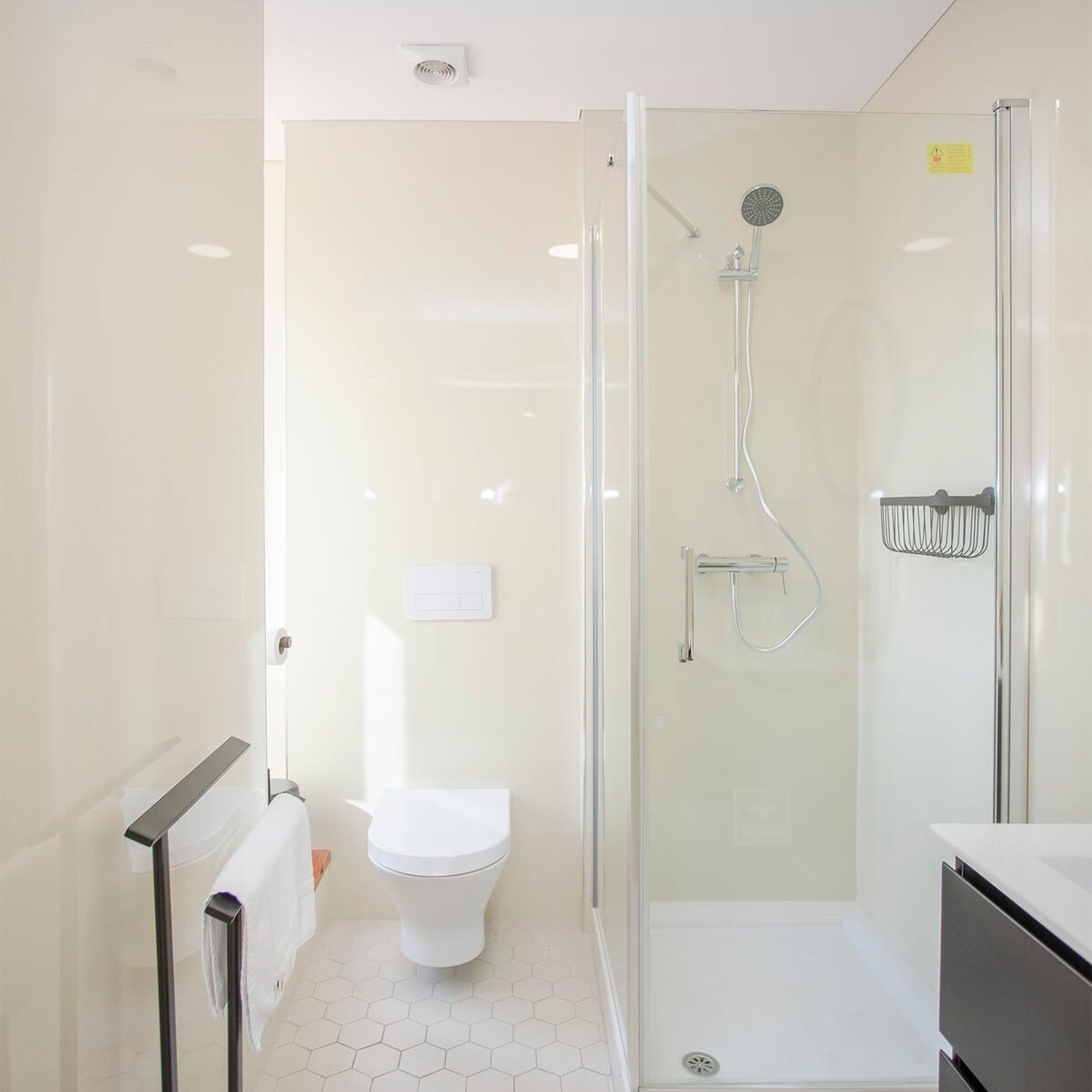 A modern bathroom with a glass-enclosed shower, a white toilet, and a white sink.