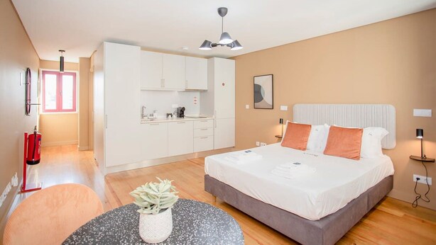 A modern bedroom with a large bed, a small kitchenette, and a dining area. - Liiiving in Porto Historic Cl Rigos Studio - 4F (Porto)