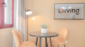 A small dining area with two chairs, a round table, a potted plant, and a wall-mounted sign that reads "Living is easy". - Liiiving in Porto Historic Cl Rigos Studio - 4F (Porto)