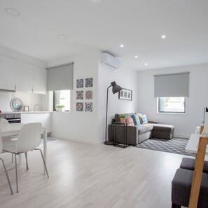 Un appartement moderne et bien éclairé, comprenant une cuisine, un coin repas et un salon.