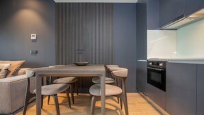 Eine moderne Küche mit Essbereich, ausgestattet mit einem Holztisch, passenden Stühlen und eingebauten Geräten.
