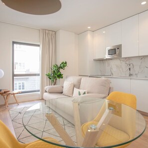 A modern living room with a glass coffee table, a sofa, and a yellow chair. - Liiiving in Porto - City Design Apartment G (Porto)