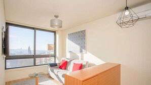 A modern living room with a large window, a sofa, a glass table, and a wooden cabinet. - Liiiving in Porto Downtown View Apartment (Porto)