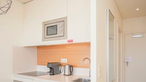 A compact kitchenette with a microwave, coffee maker, kettle, and oven. - Liiiving in Porto Downtown View Apartment (Porto)