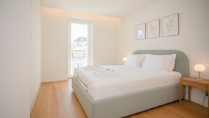 Una camera da letto con un letto, un comodino con una lampada e una finestra vista edifici.