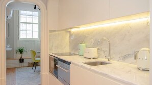 Une cuisine moderne avec des meubles blancs, un plan de travail en marbre et des appareils électroménagers en acier inoxydable.