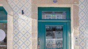Une porte de couleur bleu-vert avec un portail en métal, une plaque numérotée et un mur orné de motifs.