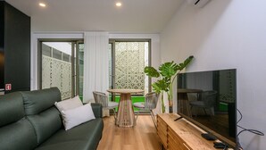 Una sala de estar moderna con un sofá, una mesa de centro de madera y un televisor.