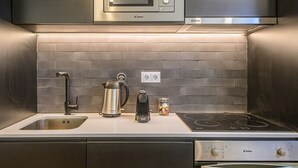 Una cocina moderna con electrodomésticos de acero inoxidable, un lavamanos doble y un horno empotrado.