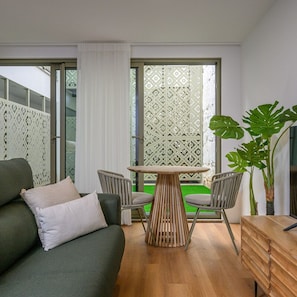 Un soggiorno moderno con un divano verde, due poltrone, un tavolo in legno e una pianta grande.