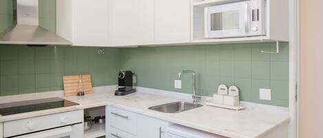 A compact kitchen with white cabinets, a microwave, a coffee maker, and a dishwasher.