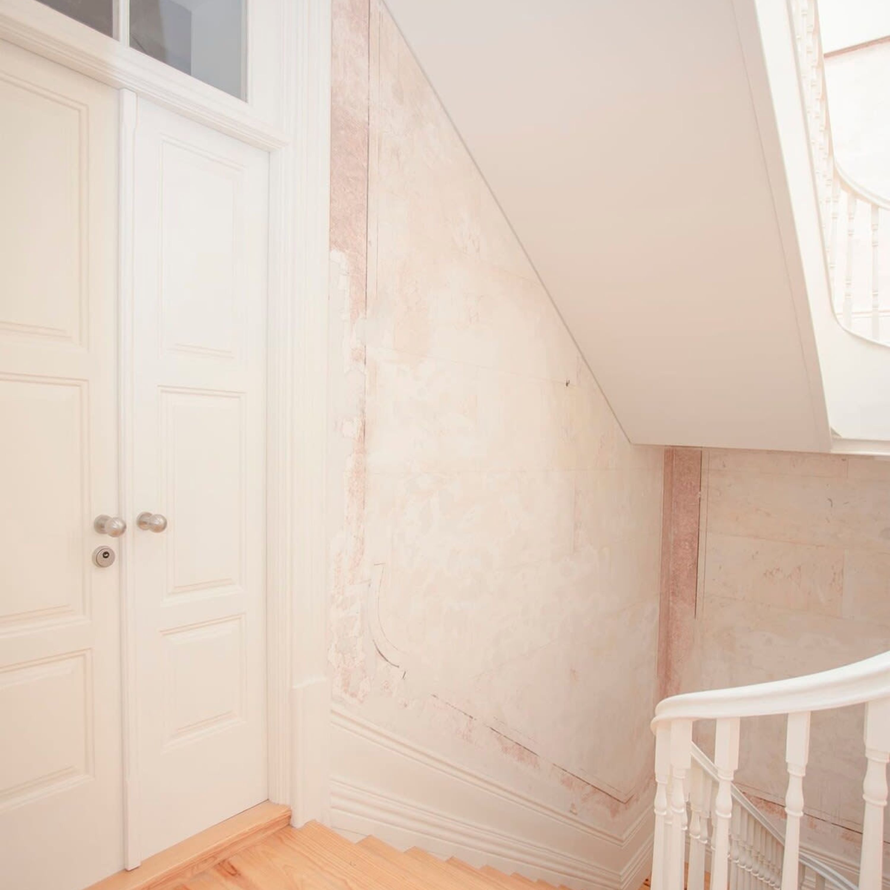 A room with a white door, a staircase, and a textured wall.