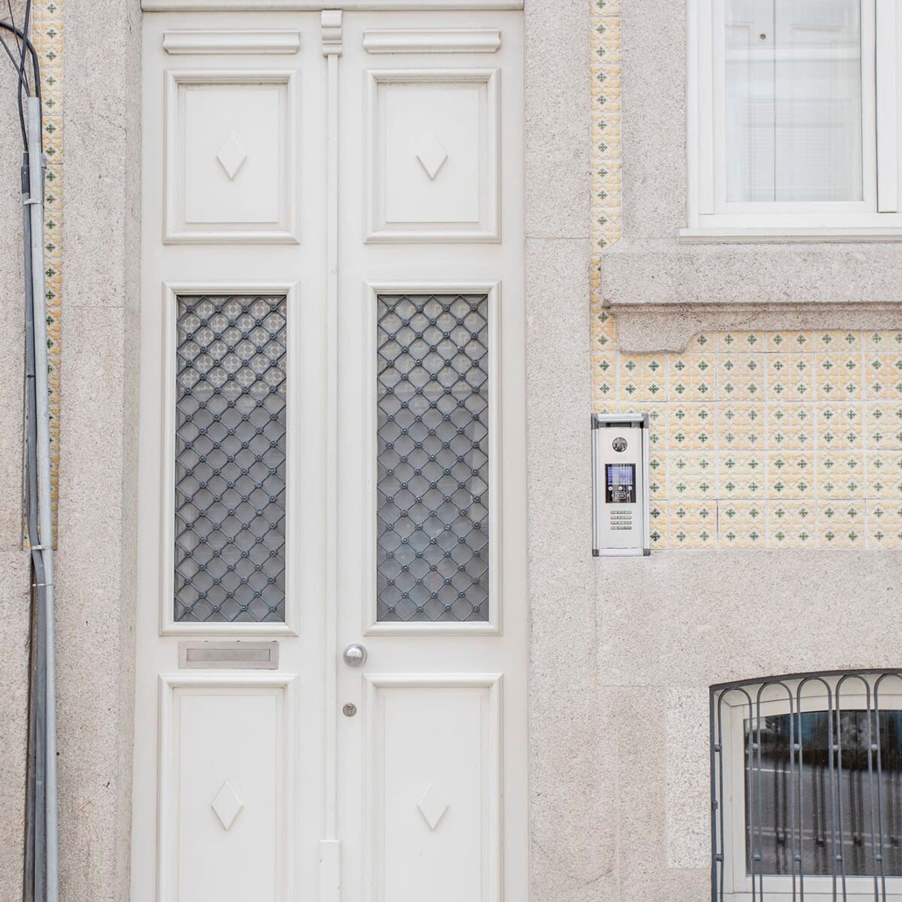 A white double door with diamond-patterned glass panels and a keypad lock.