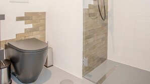 Un baño moderno con cabina de ducha de vidrio, inodoro y lavamanos.