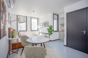 A modern hotel room with a bed, a round table with chairs, a desk, a plant, and a large wardrobe. - Liiiving in Porto - City Design Studio I (Porto)