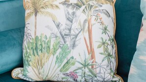 A teal sofa with a tropical-themed pillow. - Liiiving in Porto - Soho Urban Retreat (Porto)