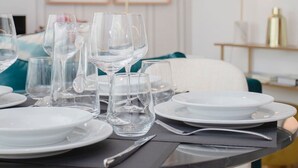 A dining table set with plates, glasses, and cutlery, with a modern interior and artwork on the wall. - Liiiving in Porto - Soho Urban Retreat (Porto)