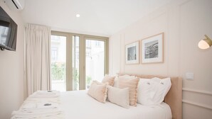 A hotel room with a large bed, a flat-screen TV mounted on the wall, and a window with curtains. - Liiiving in Porto - Soho Urban Retreat (Porto)