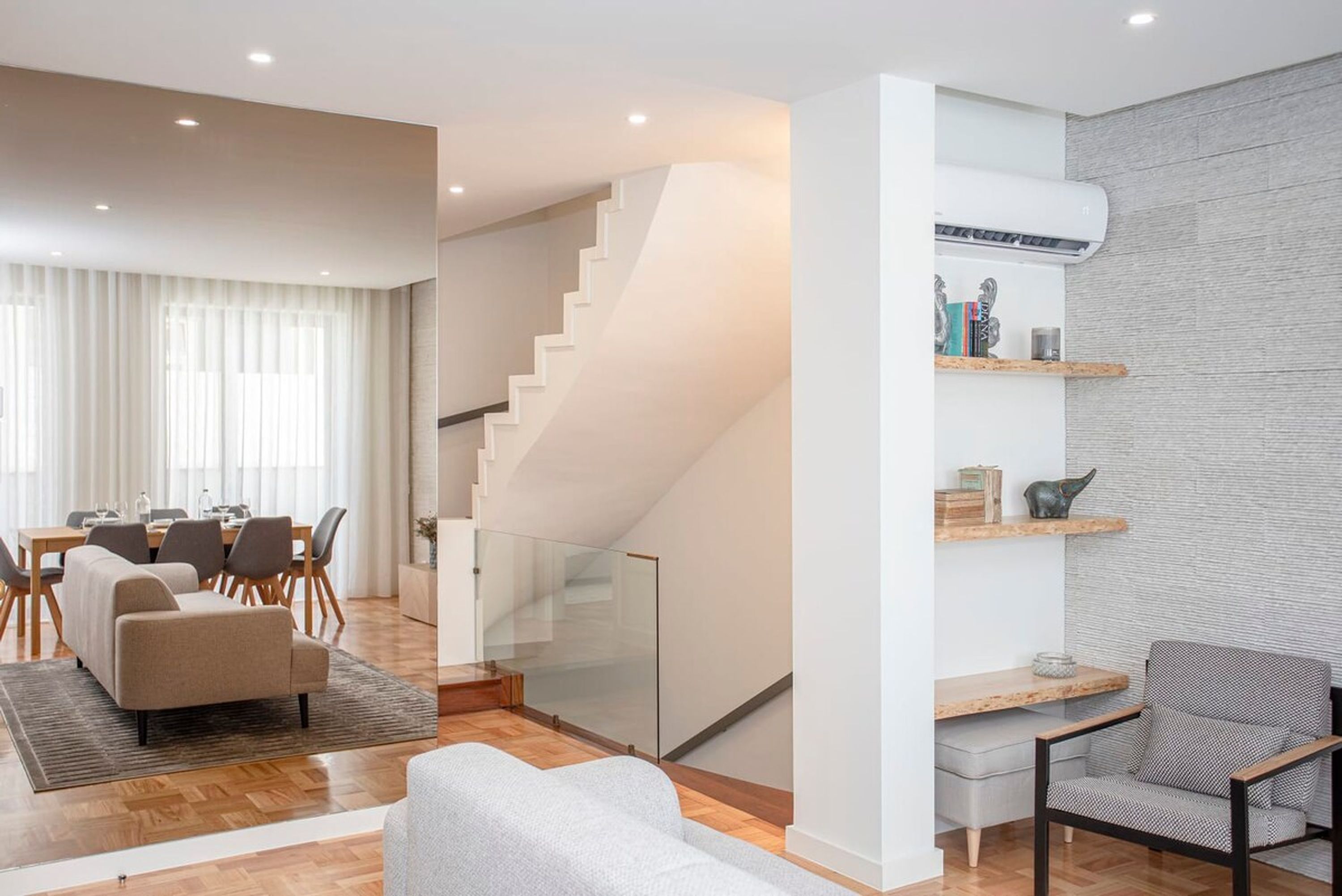 Una sala de estar moderna con una escalera, un comedor y un pequeño espacio de trabajo.