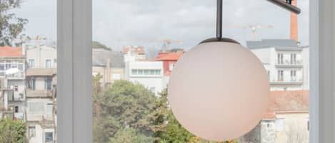 Un balcón con dos sillas de mimbre y una lámpara colgante.