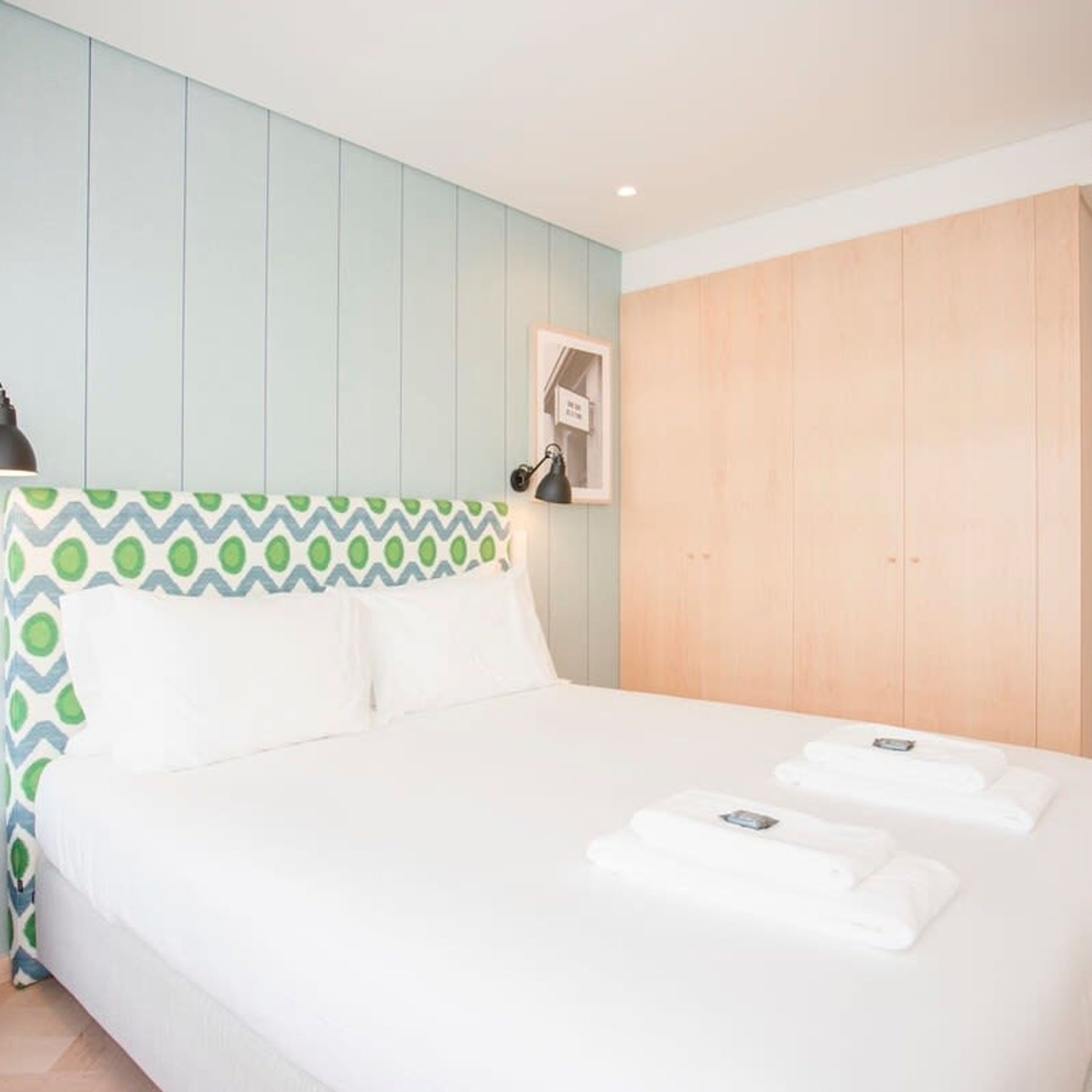 Ein Hotelzimmer mit einem Bett, einem Holzschrank und einer Wandleuchte.