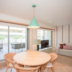 Relax in this stylish living room with a round table, wicker chairs, and a flat-screen TV.