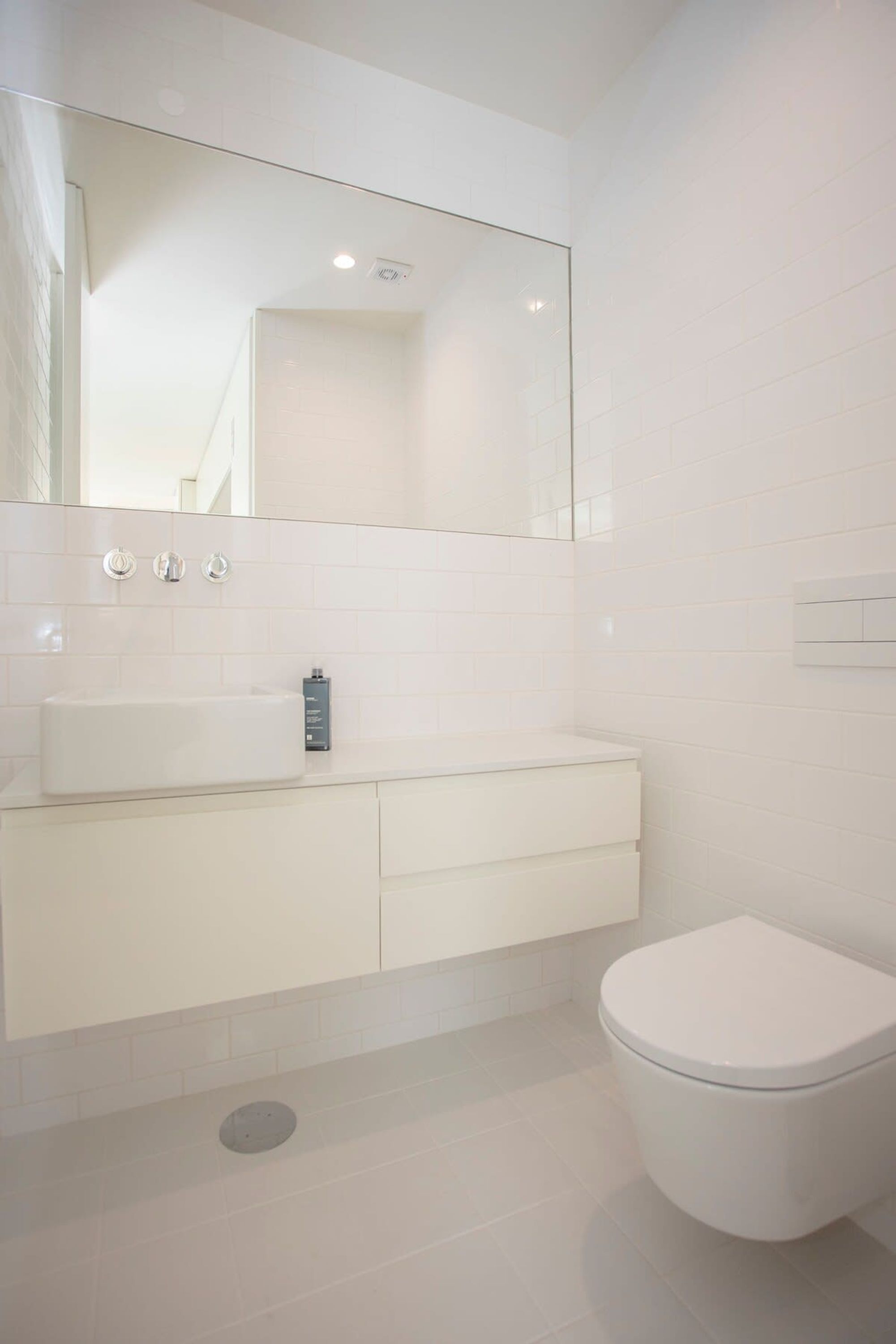 A modern bathroom with a white sink, mirror, and toilet.