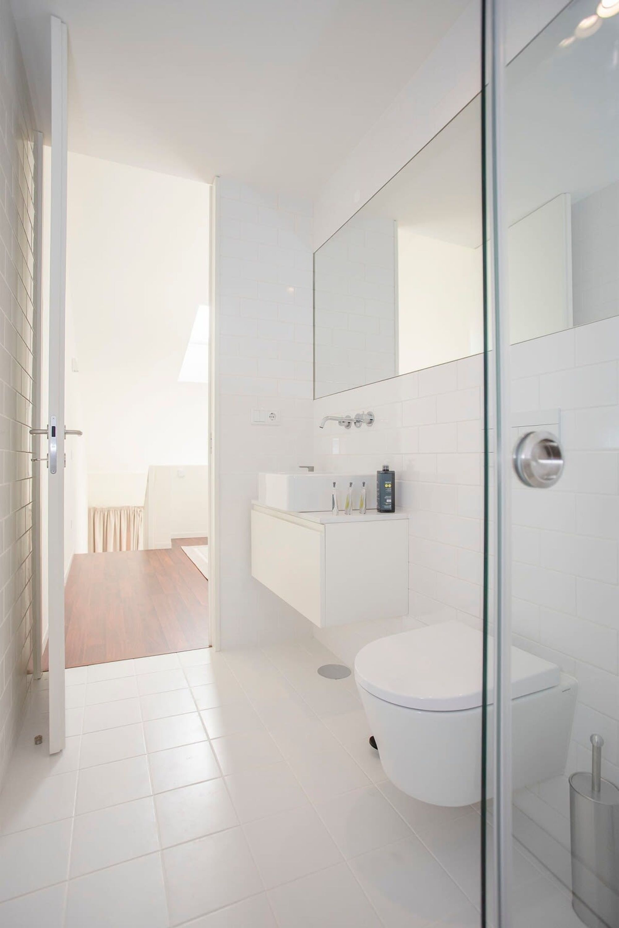 A modern bathroom with a glass shower enclosure, a white toilet, and a vanity with a mirror.